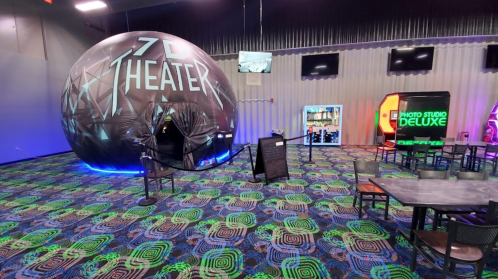 A colorful entertainment space featuring a 7D theater entrance, arcade games, and seating areas.
