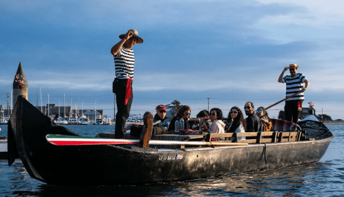 A group of people in striped shirts enjoying a boat ride on a calm waterway, with a scenic backdrop.