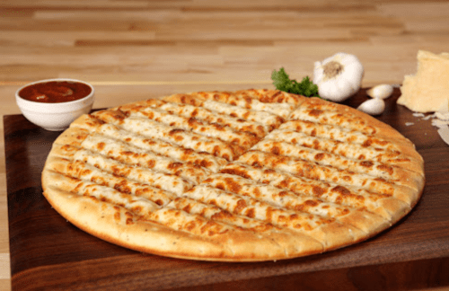 A golden-brown cheese pizza on a wooden board, accompanied by marinara sauce, garlic, and cheese.