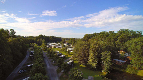 Aerial view of a mobile home park surrounded by trees under a clear blue sky.