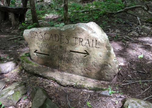 A stone sign marking the Cascades Trail, with arrows pointing left to Cascader 1 and right to Parking Lot.