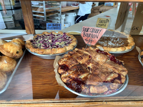 A display of delicious pies: sour cherry bourbon and blueberry, in a bakery window.
