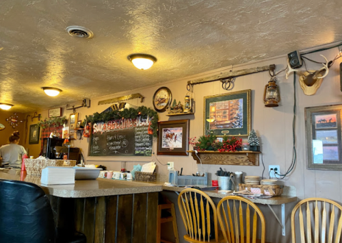 Cozy café interior with wooden counter, festive decorations, and a chalkboard menu on the wall.