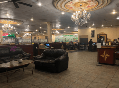 Interior of a spacious restaurant with chandeliers, seating areas, and a warm ambiance.