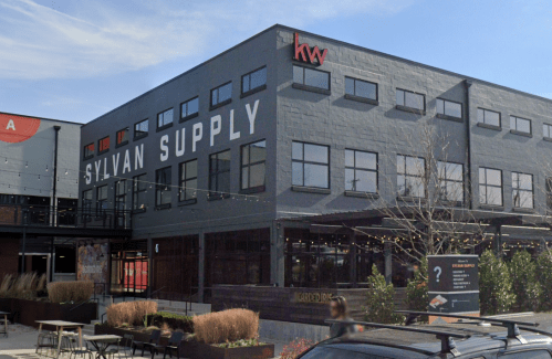 Exterior view of Sylvan Supply building with large windows and signage, featuring a clear blue sky.
