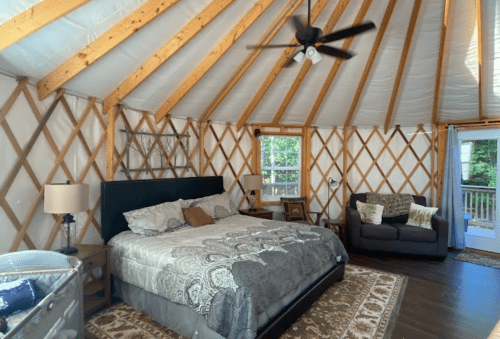 Cozy yurt interior featuring a king bed, seating area, and large windows with natural light.