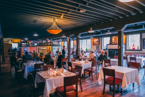A cozy restaurant interior with tables set for dining, patrons enjoying meals, and warm lighting.