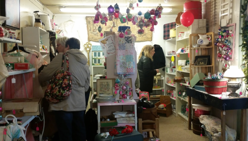 A cozy shop filled with vintage items, with customers browsing among colorful decorations and shelves.