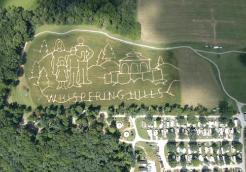 Aerial view of a large grass carving depicting a family and trees, labeled "Whispering Hills."