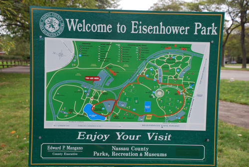 Sign displaying a map of Eisenhower Park, highlighting paths, facilities, and park features for visitors.