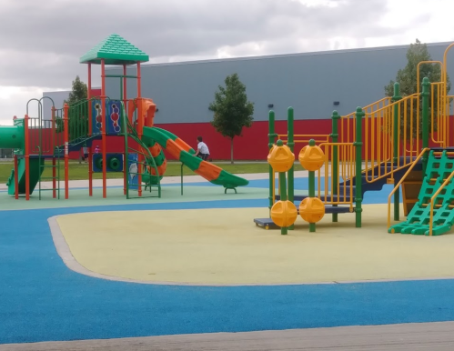 Colorful playground with slides, climbing structures, and play equipment on a bright blue and yellow surface.