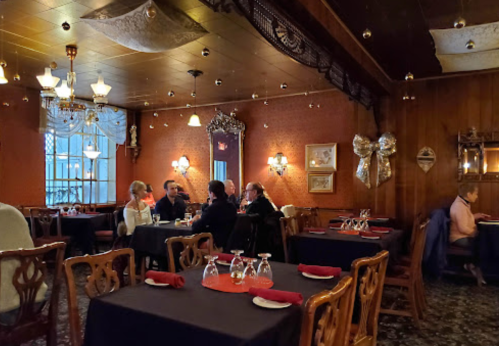 Cozy restaurant interior with dark tables, elegant decor, and diners engaged in conversation under soft lighting.