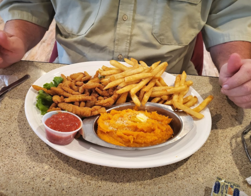 A plate with crispy fried chicken strips, French fries, and a side of sweet potato mash with butter and salsa.
