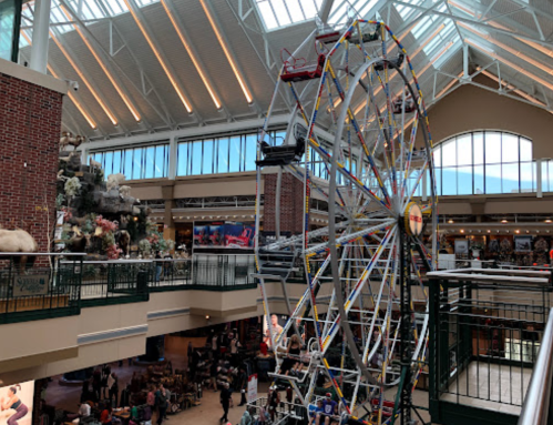 A colorful ferris wheel inside a spacious shopping mall with high ceilings and natural light.