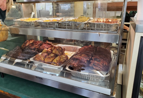 A display case filled with various cooked meats and side dishes at a restaurant, including ribs and chicken.