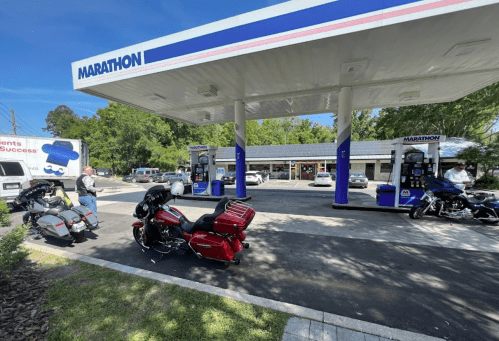 Two motorcycles parked at a Marathon gas station with a convenience store in the background on a sunny day.