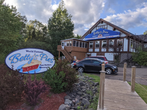 Sign for Betty's Pies in Two Harbors, Minnesota, with a charming building and outdoor seating area.