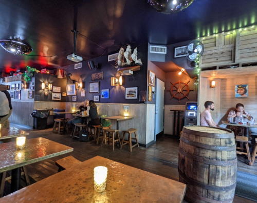 Cozy restaurant interior with wooden tables, nautical decor, and patrons enjoying their meals in a warm atmosphere.