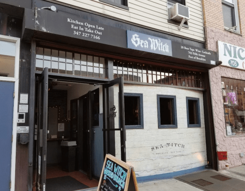 Exterior of Sea Witch restaurant with a sign stating "Kitchen Open Late" and a takeout number.