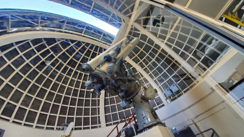 A large telescope inside a dome with a glass ceiling, showcasing its intricate machinery and structure.