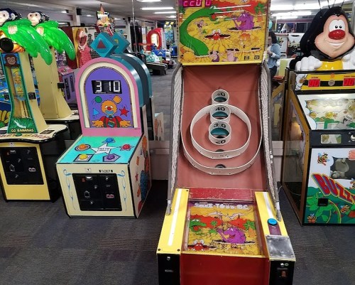 Colorful arcade games in a game room, featuring a skee-ball machine and a ticket redemption game.