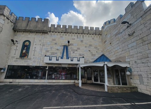 A castle-themed building with stone walls, a blue roof entrance, and large windows.