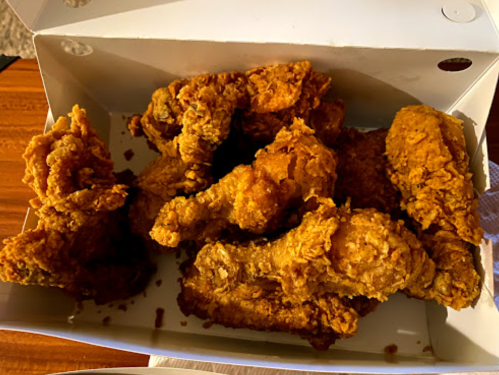 A box of crispy, golden-brown fried chicken pieces arranged neatly inside.