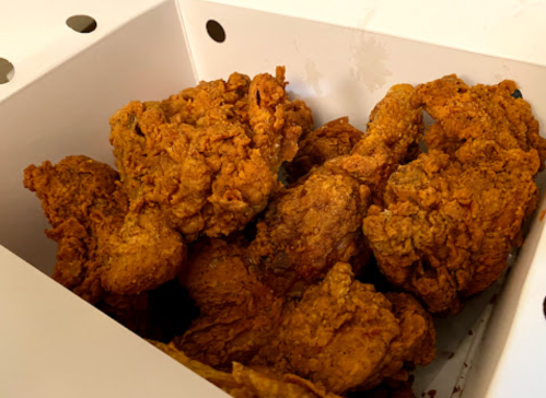 A box filled with crispy, golden-brown fried chicken pieces.