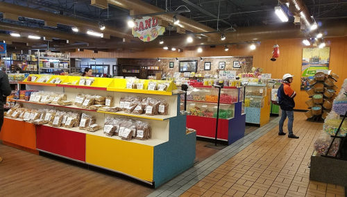 A colorful candy store interior with shelves filled with various candies and customers browsing.
