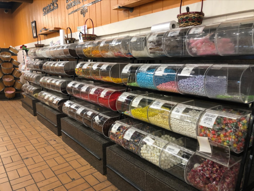 A colorful display of various candies in clear bins on shelves at a candy store.