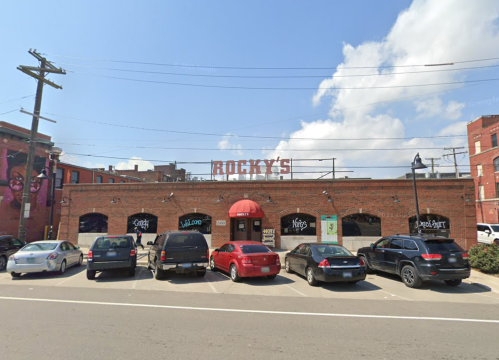Exterior of Rocky's restaurant with parked cars and a blue sky in the background.