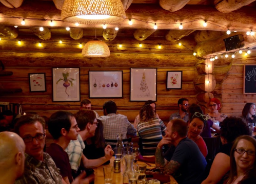 A cozy restaurant interior with wooden walls, warm lighting, and patrons enjoying their meals and conversations.
