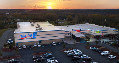 Aerial view of The Big E grocery store at sunset, surrounded by parking and trees in the background.