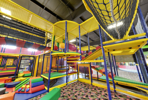 Colorful indoor play area with climbing structures, slides, and foam pits, designed for children's activities and fun.