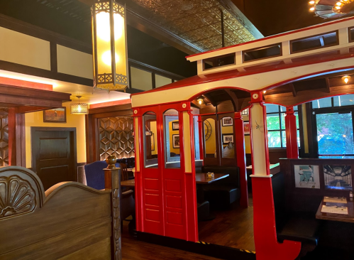 Interior of a restaurant featuring a red and white trolley booth, warm lighting, and decorative wall elements.