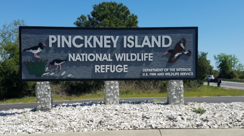 Sign for Pinckney Island National Wildlife Refuge, featuring wildlife illustrations and information about the refuge.