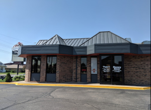 A brick restaurant building with a gray roof, featuring large windows and an "Open" sign.