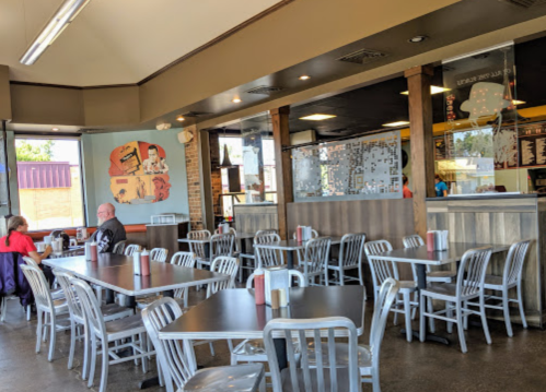 A spacious diner interior with metal tables and chairs, featuring a mural and a counter in the background.