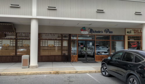 Exterior of Michele's Pies shop with a parked car in front and a sign featuring a pie graphic.
