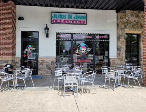 Exterior of Juke N Jive Creamery with outdoor seating and a colorful sign, inviting customers to enjoy ice cream and coffee.