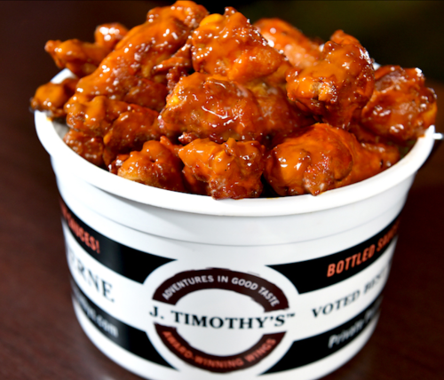 A bucket filled with saucy chicken wings, showcasing a glossy, appetizing glaze.