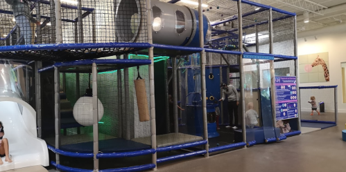 Indoor play structure with slides, climbing areas, and various activities for children in a spacious environment.