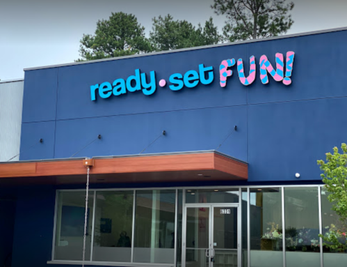 A colorful sign on a building reads "ready. set. FUN!" with a modern entrance below.