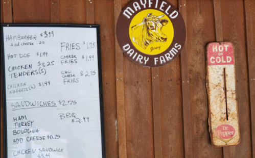 Menu board at Mayfield Dairy Farms featuring prices for burgers, hot dogs, chicken tenders, fries, and sandwiches.
