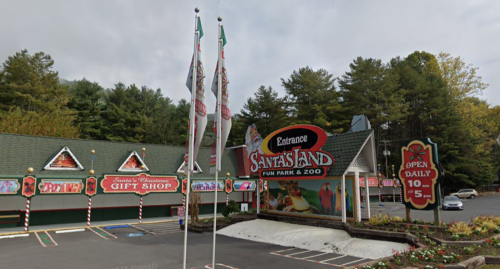 Entrance to Santa's Land Fun Park & Zoo, featuring a gift shop and colorful signage, surrounded by trees.