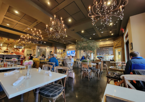 A cozy restaurant interior with chandeliers, tables, and patrons enjoying their meals in a warm atmosphere.