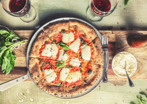A delicious pizza with mozzarella and basil, served with red wine and garnished with fresh basil and cheese.