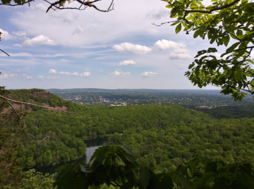 A scenic view of lush green hills and a river, under a partly cloudy sky.