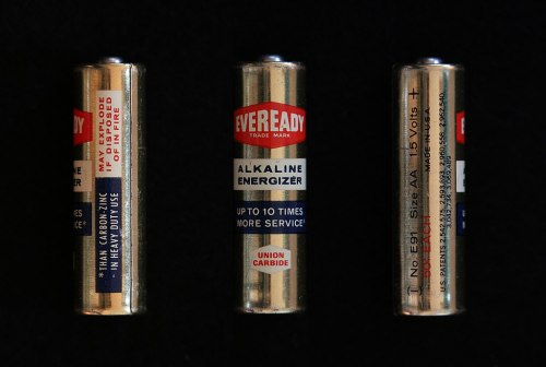 Three views of an Eveready alkaline battery, labeled with specifications and branding, against a black background.