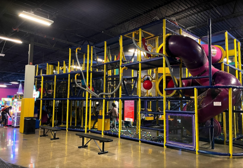 A colorful indoor play structure with slides, climbing areas, and ball pits in a family entertainment center.